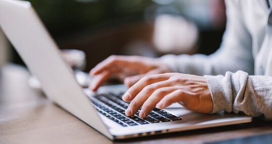 Close up of hands typing on a laptop.