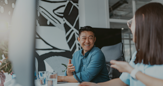 Handsome asian businessman working on laptop sitting in coworking on colleagues background